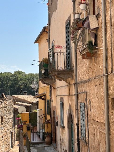 A village lane with a for-sale sign on a balcony