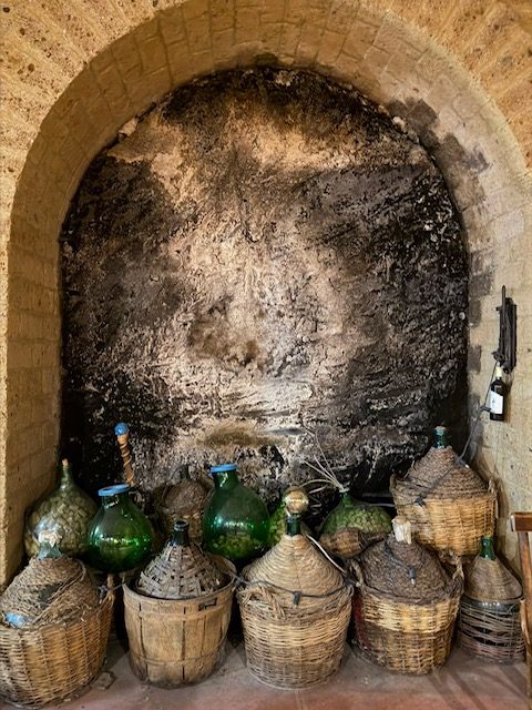 Wicker-covered demijohns under a stone arch