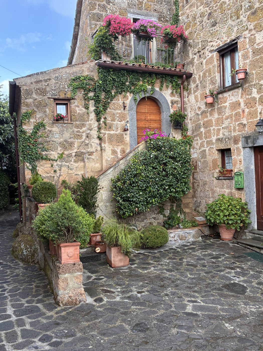 A stone house in Civita with flowers on the balcony and ivy along the steps